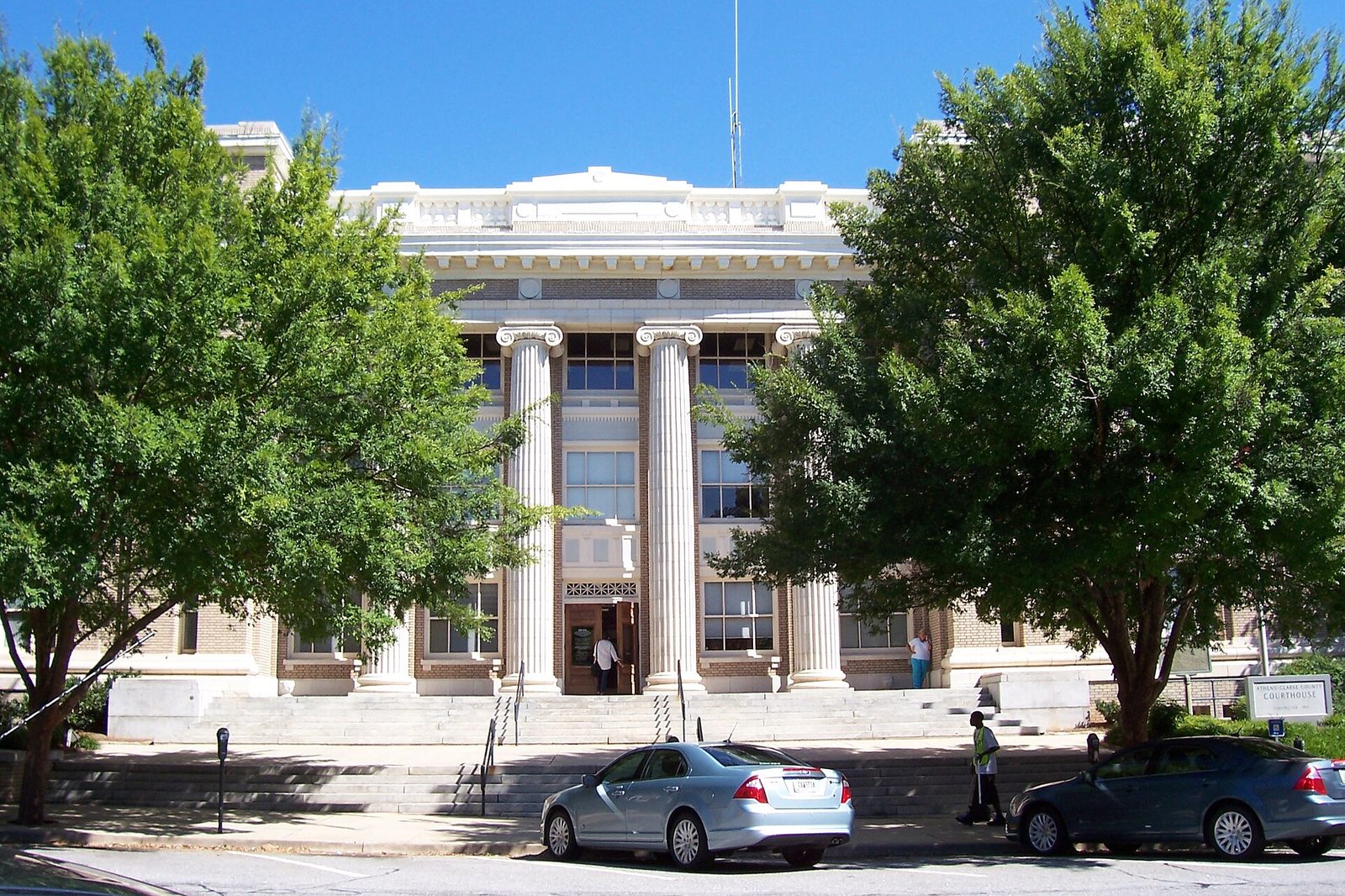 The white-columned classical facade of the Athens-Clarke County Courthouse behind shade trees in downtown Athens, Georgia