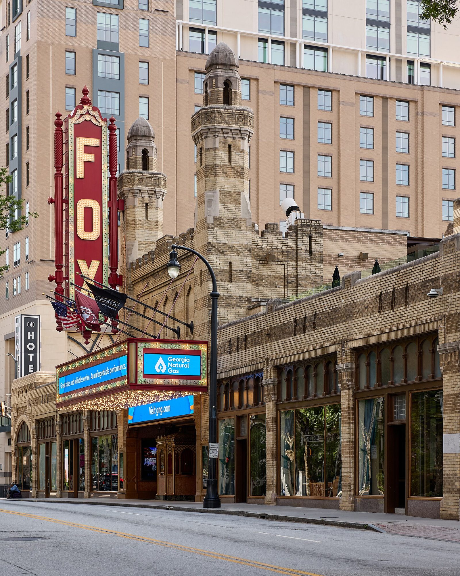 The red vertical FOX marquee sign and Moorish stone minarets of the Fox Theatre on Peachtree Street in Atlanta, seen from street level in afternoon light