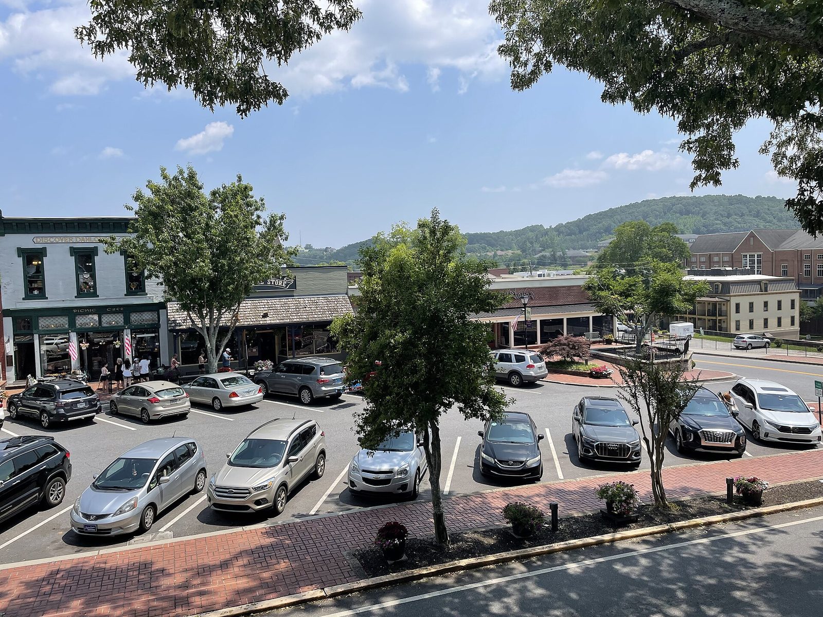 Dahlonega's town square seen from above, with storefronts, angled parking, shade trees and wooded hills behind