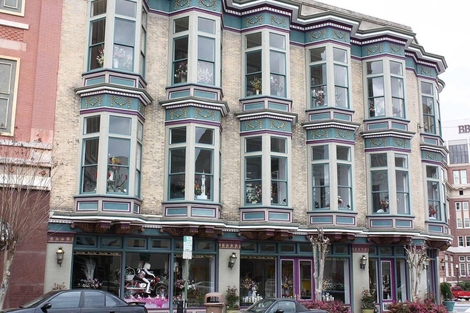 An ornate restored Victorian commercial building with bay windows painted teal and purple in downtown Macon, Georgia