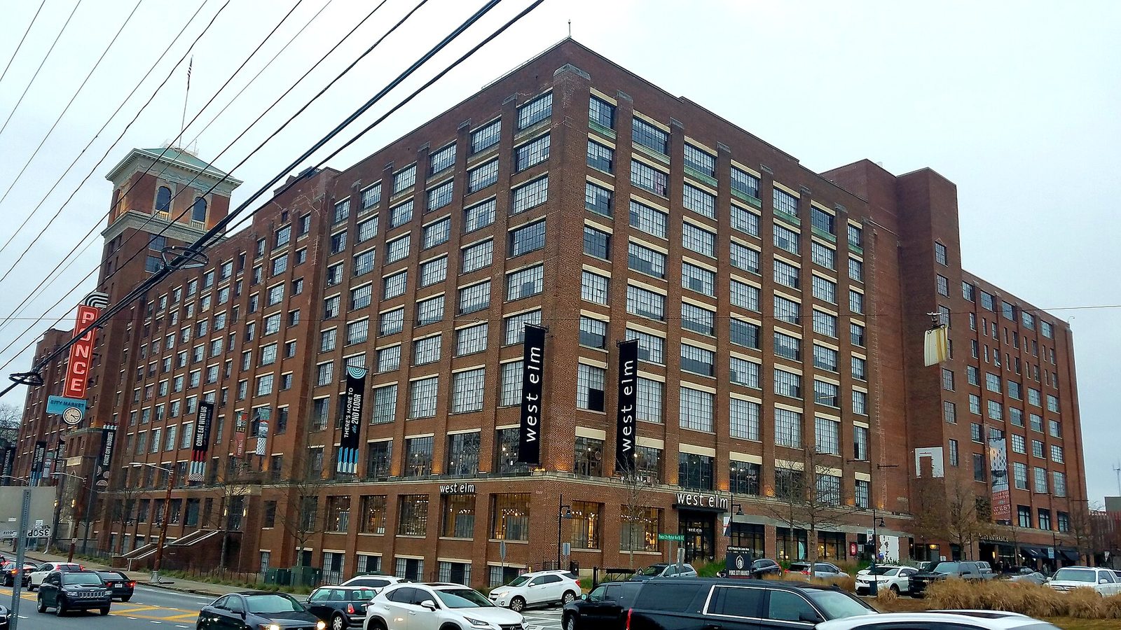 The long brick facade of Ponce City Market in Atlanta, a converted Sears warehouse with rows of tall windows and a corner tower, seen from the street