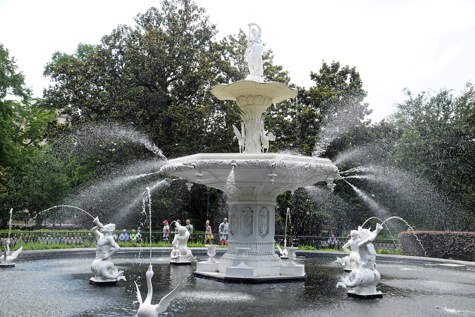 The white cast-iron fountain in Forsyth Park, Savannah, spraying water with live oaks behind it