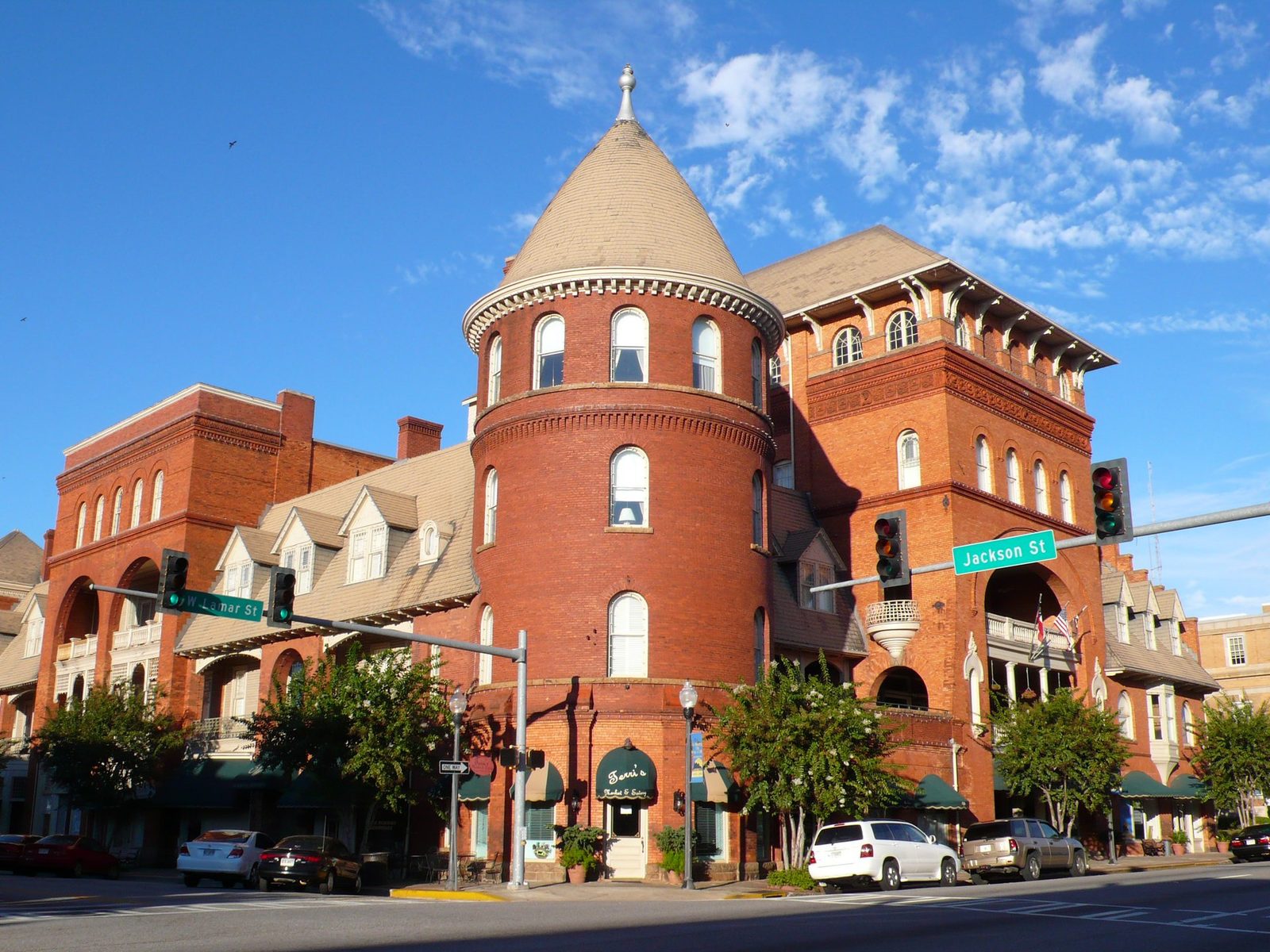The red brick Windsor Hotel in Americus, Georgia, with its conical corner turret and arched porches, seen from the street corner under a blue sky